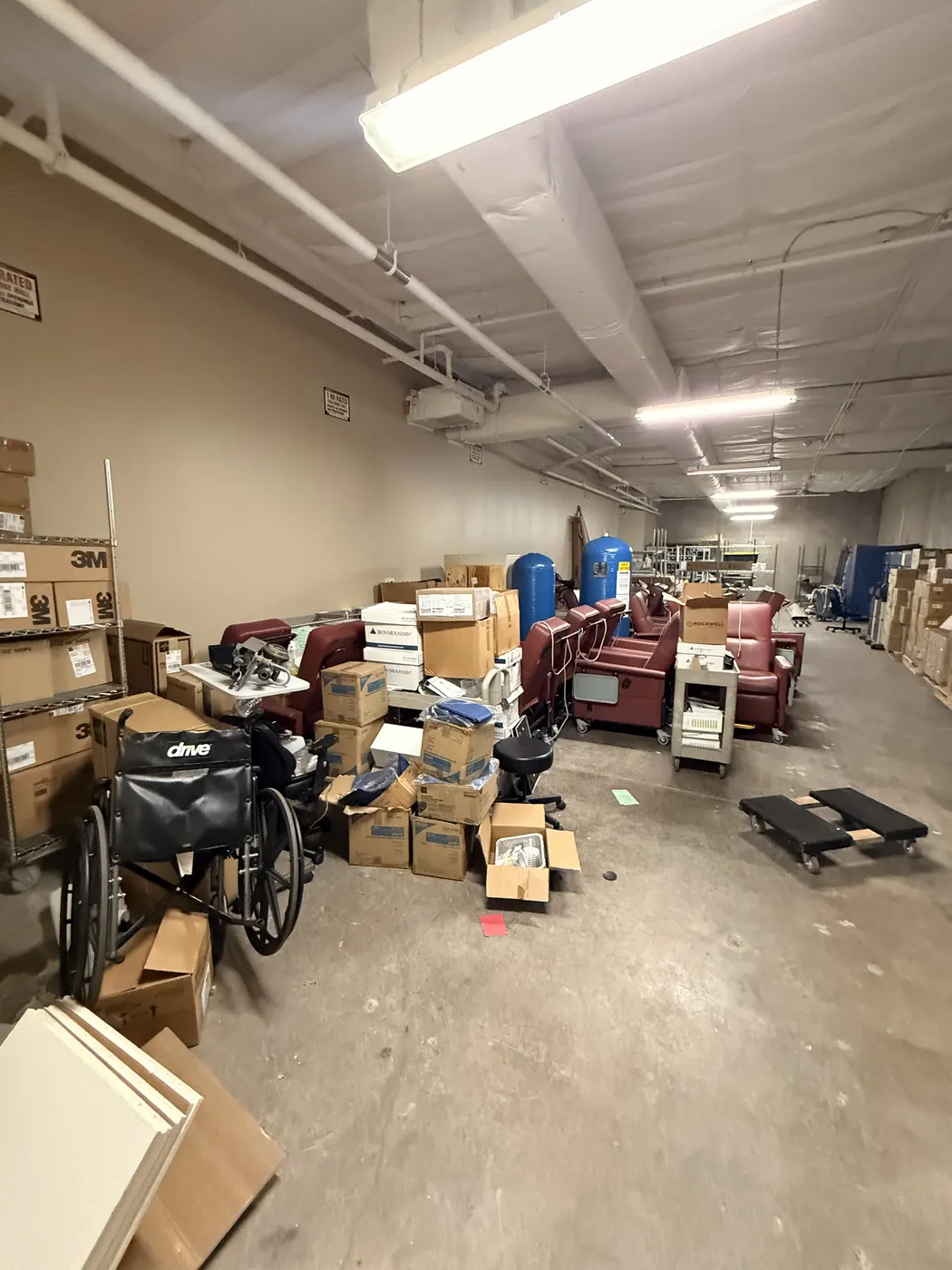 Before cleanout: stored boxes, chairs, and equipment crowding the warehouse floor.
